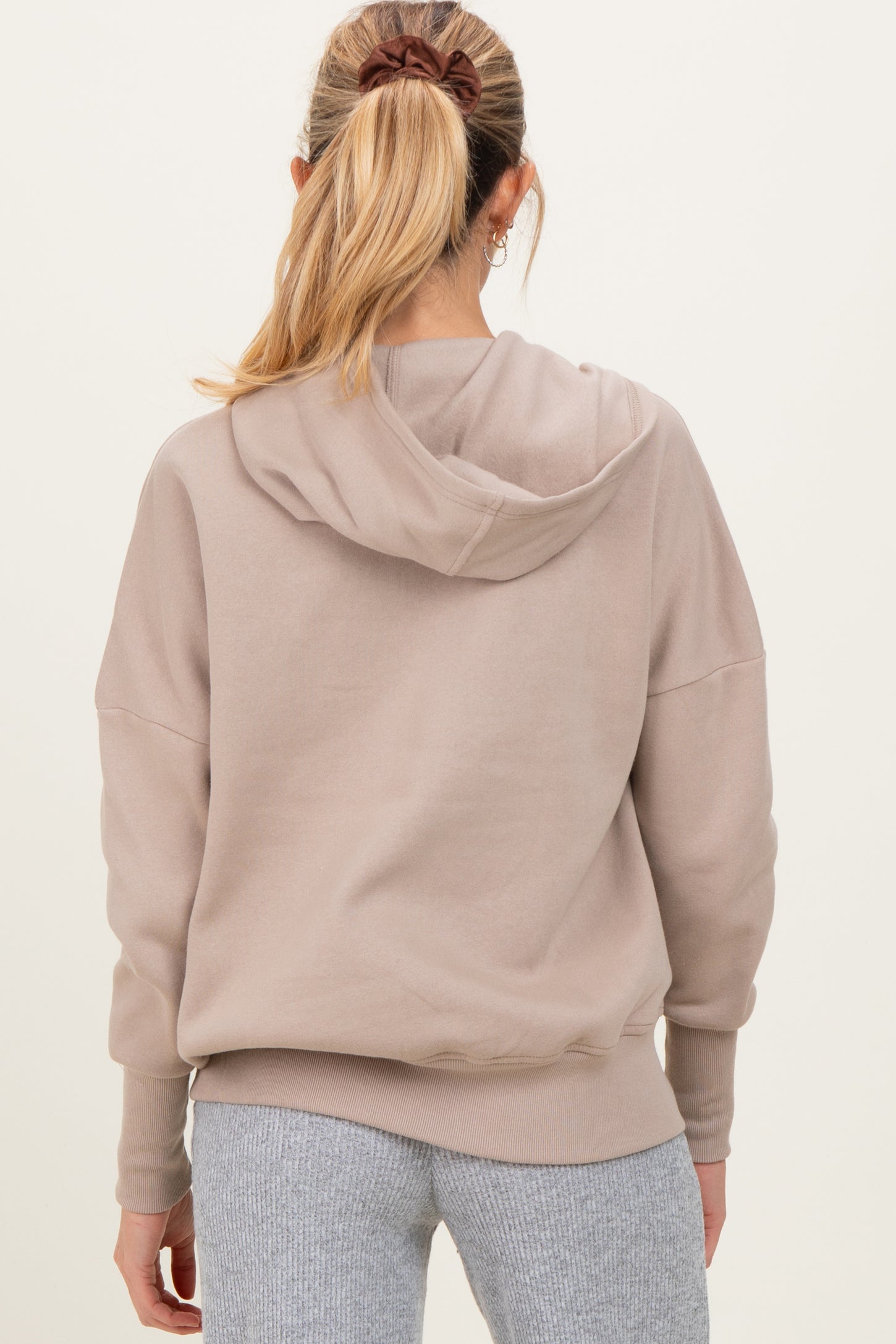 woman wearing a beige maternity hoodie with a relaxed fit and back hood detail