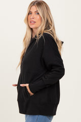 woman wearing a black oversized hoodie with kangaroo pockets and a hood, styled with light blue jeans