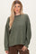 woman wearing a green oversized long sleeve sweater with a ribbed texture and relaxed shoulders