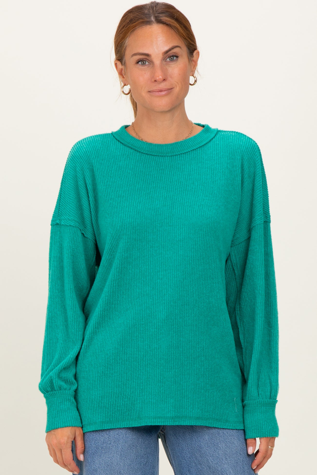woman wearing a teal oversized ribbed long sleeve sweater with a round neckline and relaxed fit