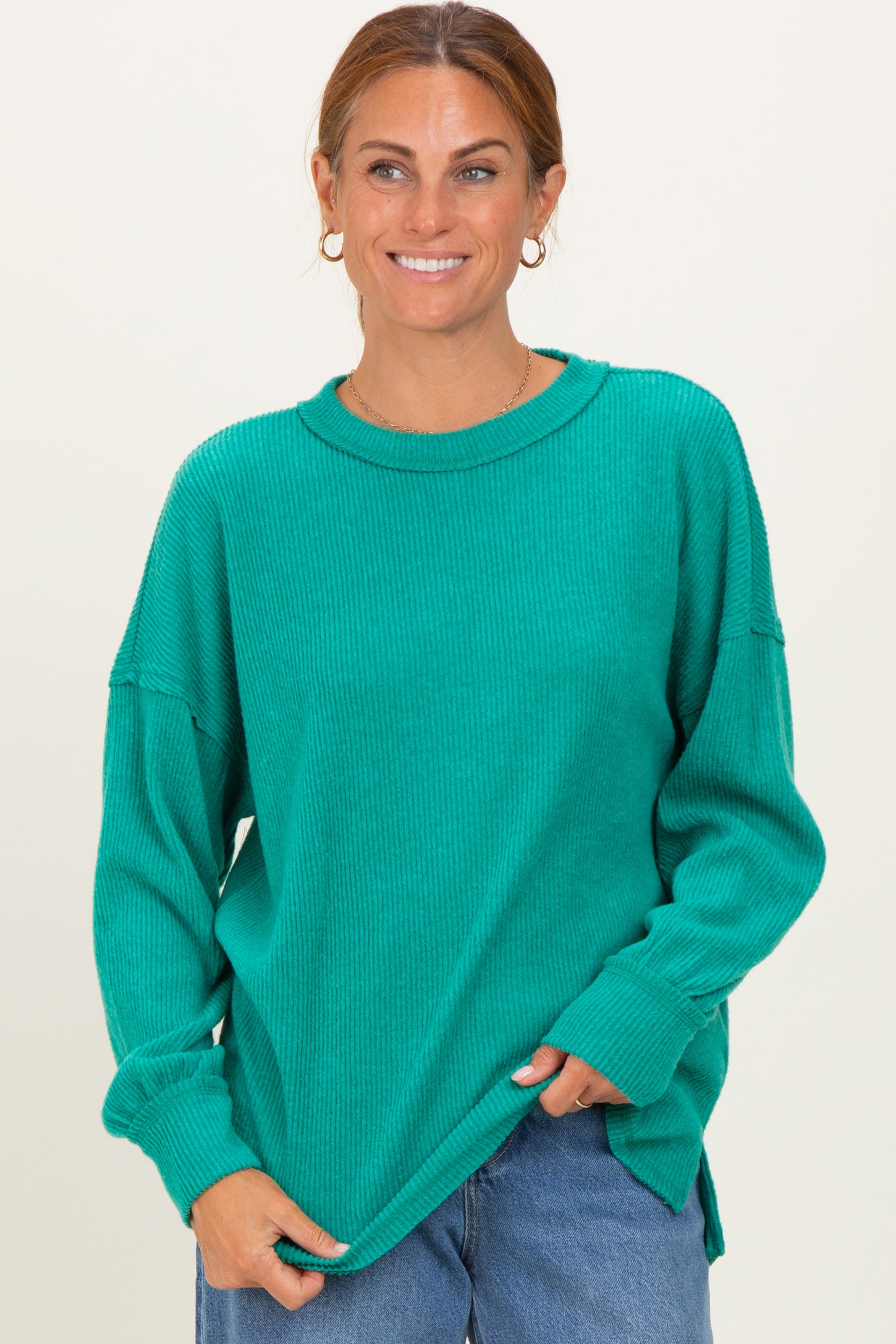 woman wearing a teal oversized ribbed sweater with long sleeves and a relaxed fit