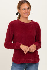 woman wearing a burgundy textured long sleeve sweater and smiling
