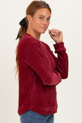 woman wearing a burgundy textured long sleeve sweater with crew neckline and relaxed fit