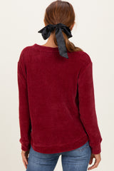 woman wearing a burgundy ribbed sweater with a relaxed fit and a black ribbon in her hair, seen from the back