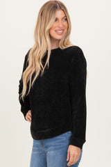 woman wearing a black textured long sleeve sweater paired with blue jeans