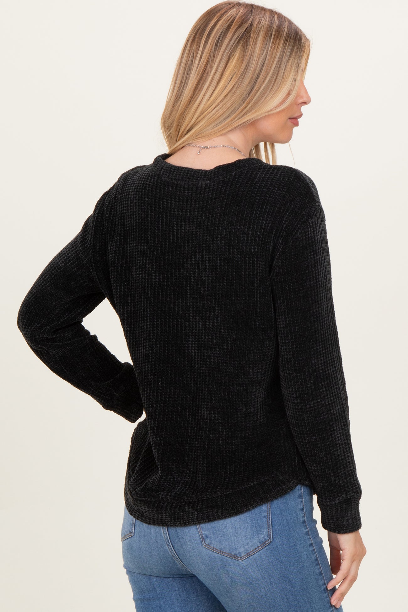 woman wearing a black ribbed long sleeve shirt with a relaxed fit and a round neckline, seen from the back