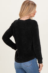 woman wearing a black ribbed long sleeve shirt with a relaxed fit and a round neckline, seen from the back