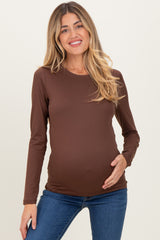 woman wearing a brown long sleeve maternity top and holding her baby bump
