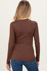 woman wearing a brown long sleeve maternity top, shown from the back, paired with blue jeans