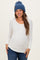 woman wearing a white long sleeve maternity top with buttons and a baby bump, paired with a blue knitted beanie and jeans