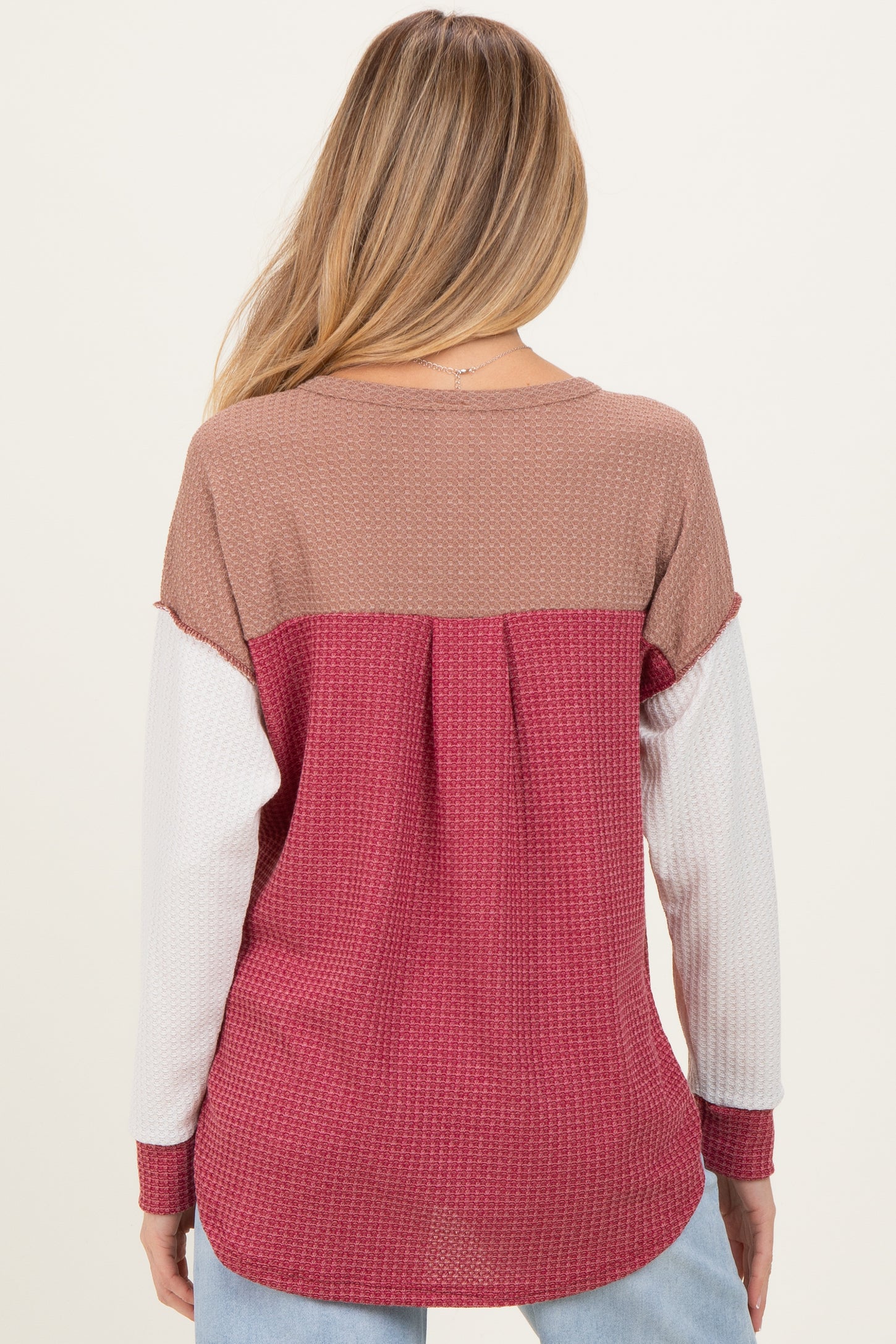 woman wearing a color-blocked maternity top in pink, brown, and white with a relaxed fit and back pleat detail