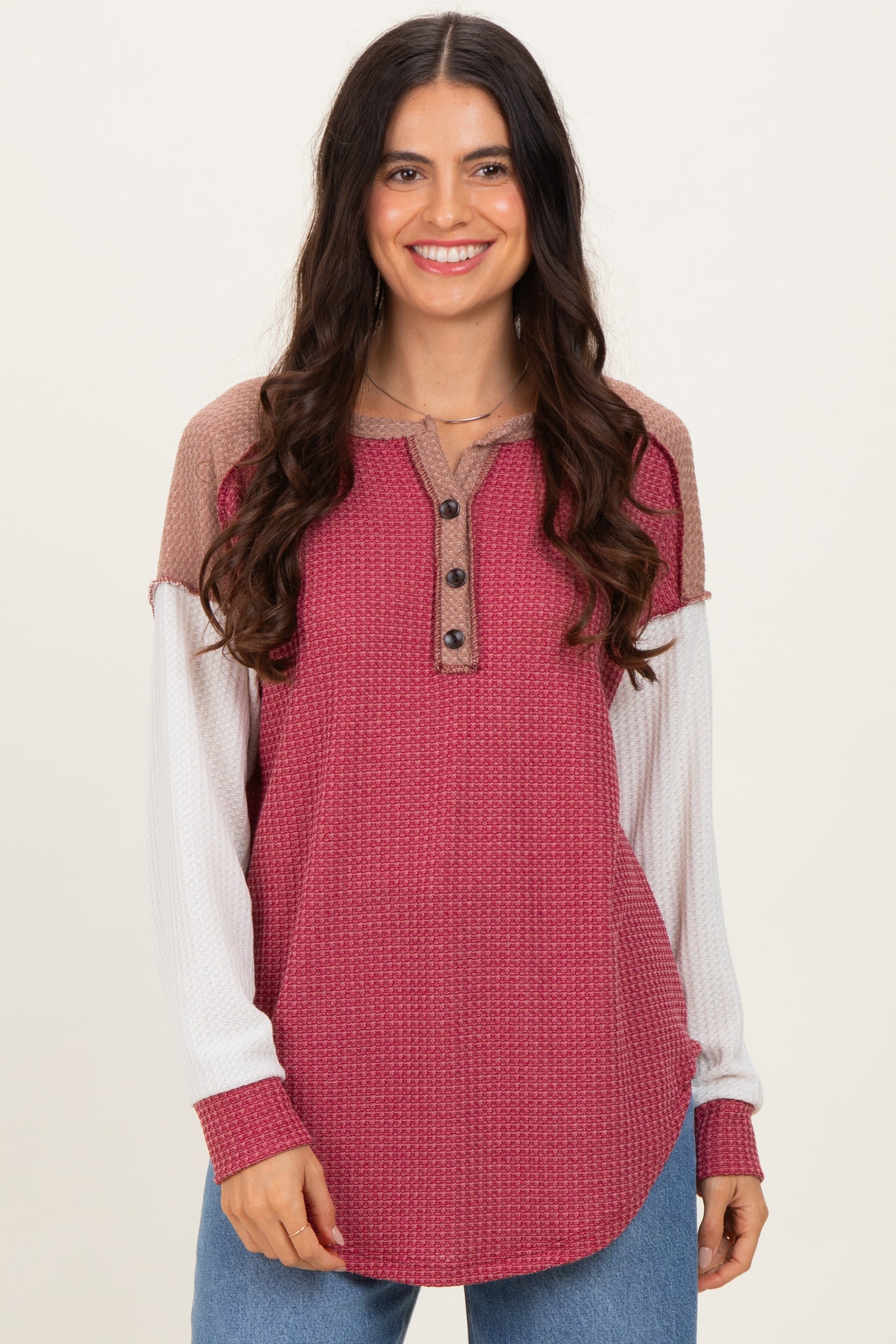 woman wearing a burgundy and beige color-blocked long sleeve top with buttons and a relaxed fit