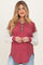 woman wearing a maroon and cream long sleeve maternity top with button details and a relaxed fit, showing her baby bump