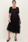 woman wearing a black maternity dress with puff sleeves and tiered tulle detailing, showing her baby bump