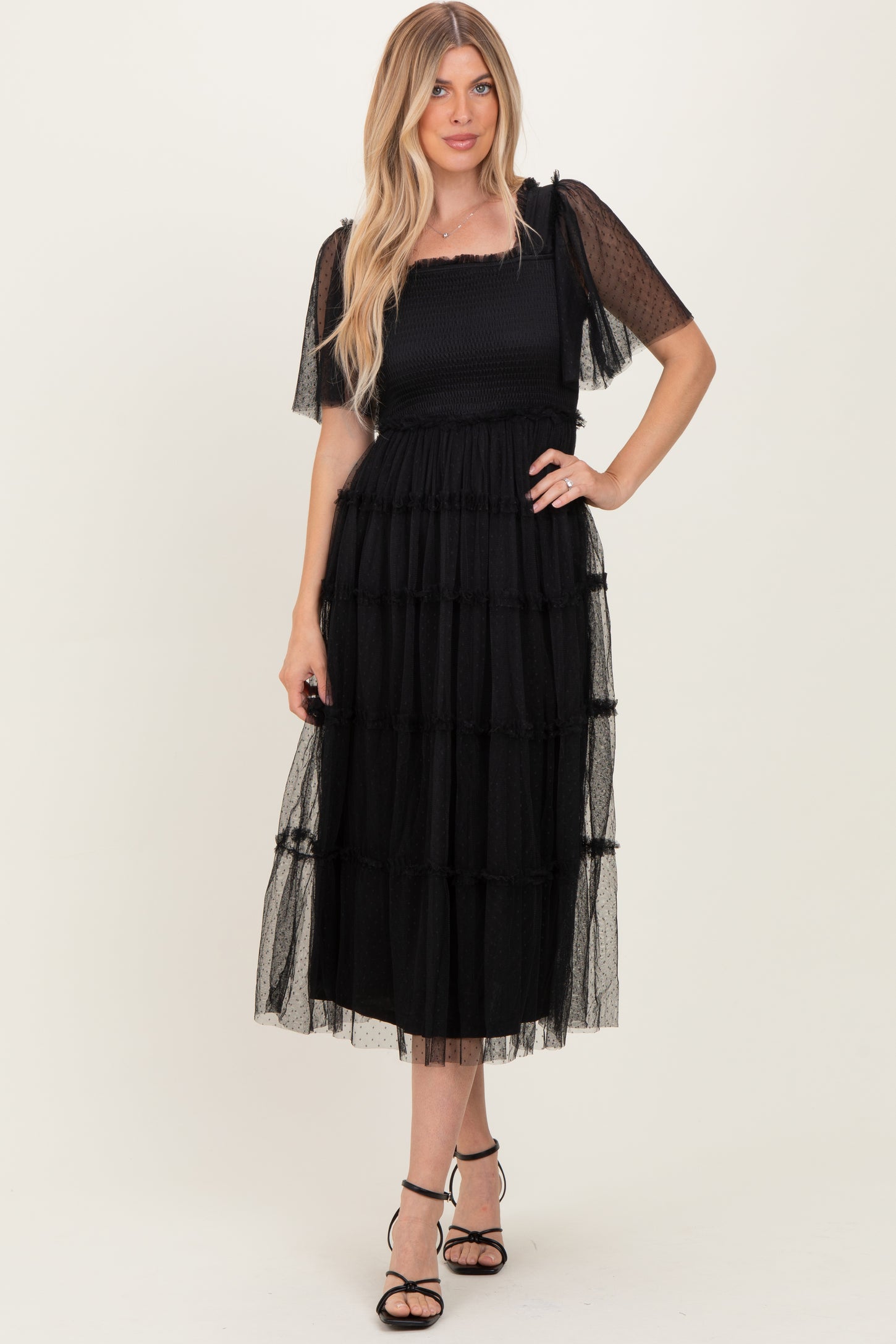 woman wearing a black tiered midi dress with short sheer sleeves and a smocked bodice