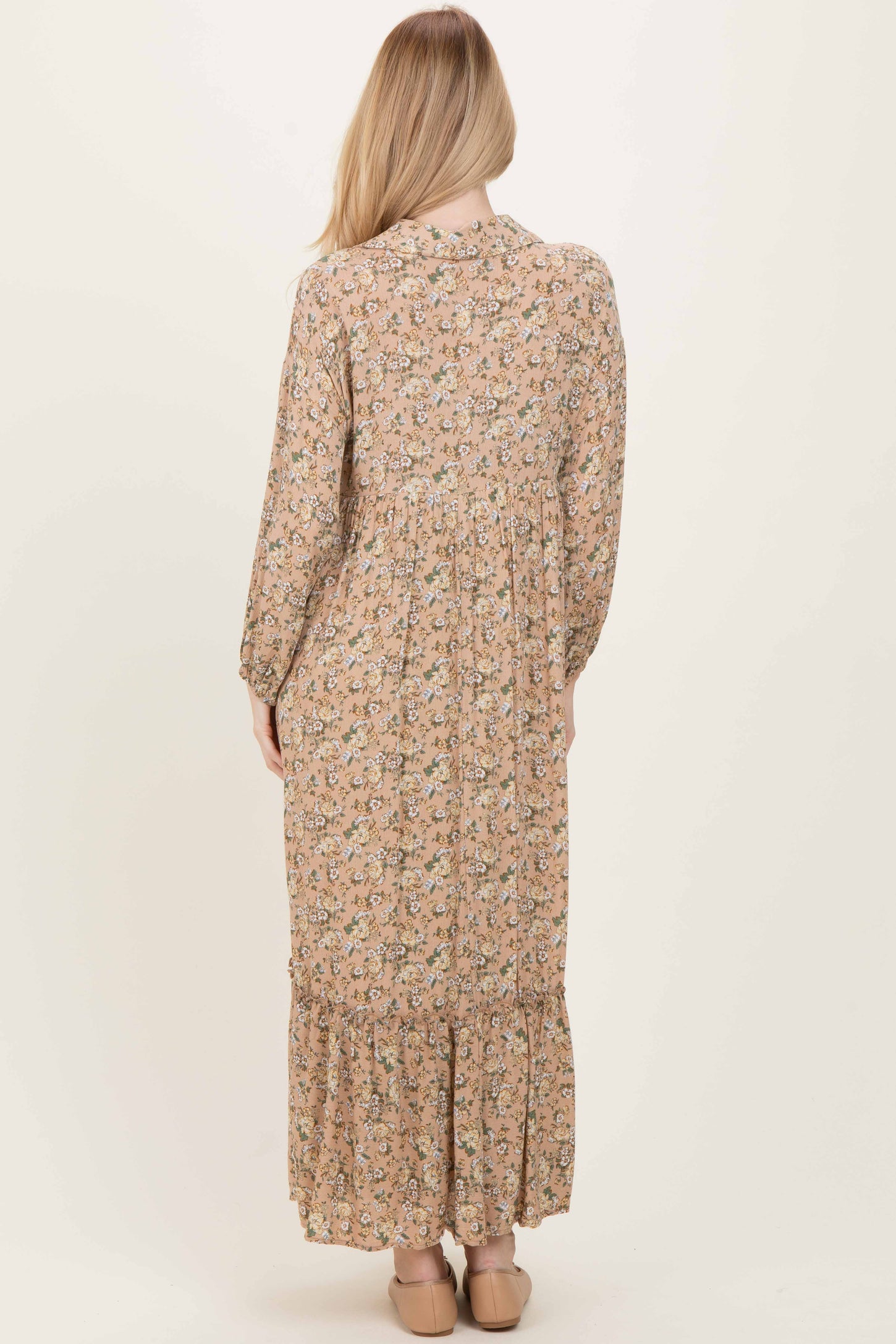 woman wearing a long floral print maxi dress with long sleeves and a tiered skirt, viewed from the back