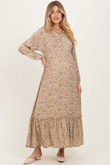 woman wearing a beige floral maternity dress with long sleeves and a tiered hem, showcasing her baby bump