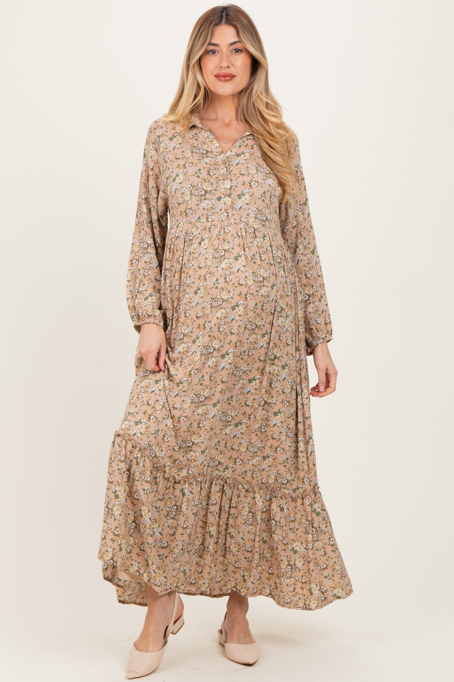 woman wearing a floral maternity dress with long sleeves and a tiered hem, showcasing her baby bump