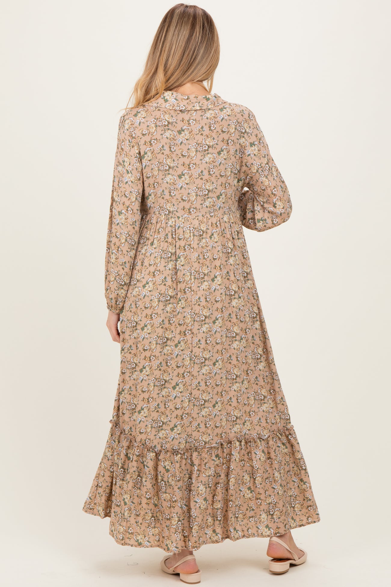 woman wearing a floral maternity maxi dress with long sleeves and a ruffled hem, showing her baby bump from the back