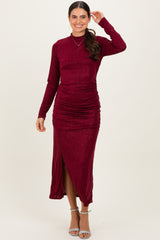 woman wearing a burgundy long sleeve shimmer dress with a fitted silhouette and side slit