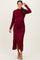 woman wearing a burgundy long sleeve shimmer dress with a fitted silhouette and side slit