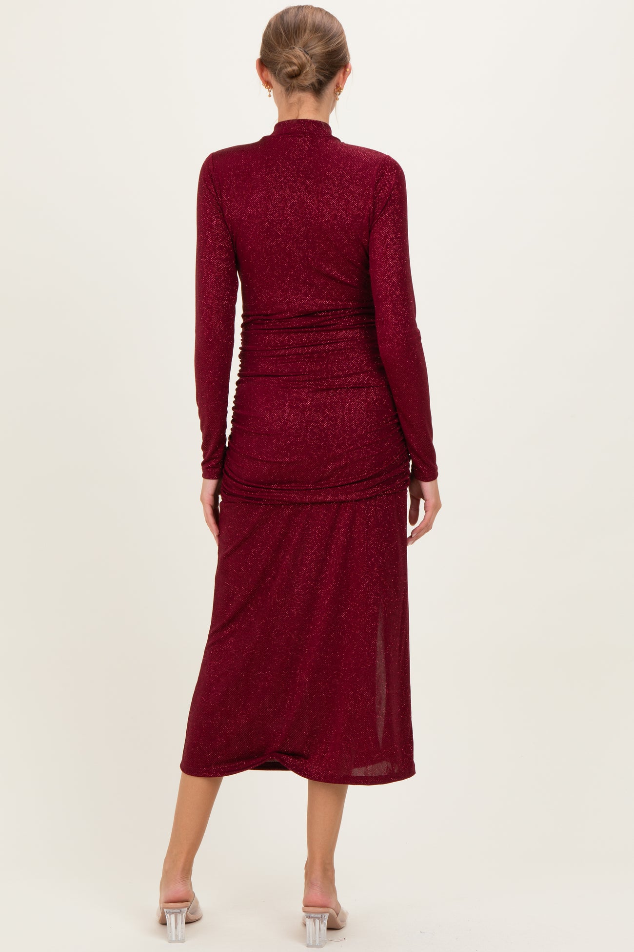 woman wearing a burgundy long sleeve maternity dress with ruched detailing and a midi length