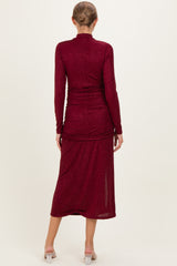woman wearing a burgundy long sleeve maternity dress with ruched detailing and a midi length