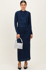 woman wearing a navy blue glitter long sleeve dress with ruched detailing and holding a silver handbag