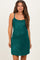 woman wearing a sparkly emerald green maternity slip dress with thin straps and a fitted silhouette, showing her baby bump