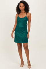 woman wearing a shimmering emerald green mini dress with thin straps and a fitted silhouette