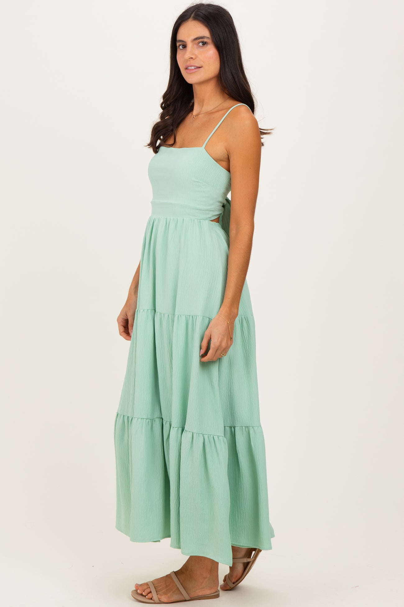 woman wearing a mint green maxi dress with tiered layers and thin straps
