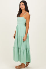 woman wearing a mint green maxi dress with tiered layers and thin straps