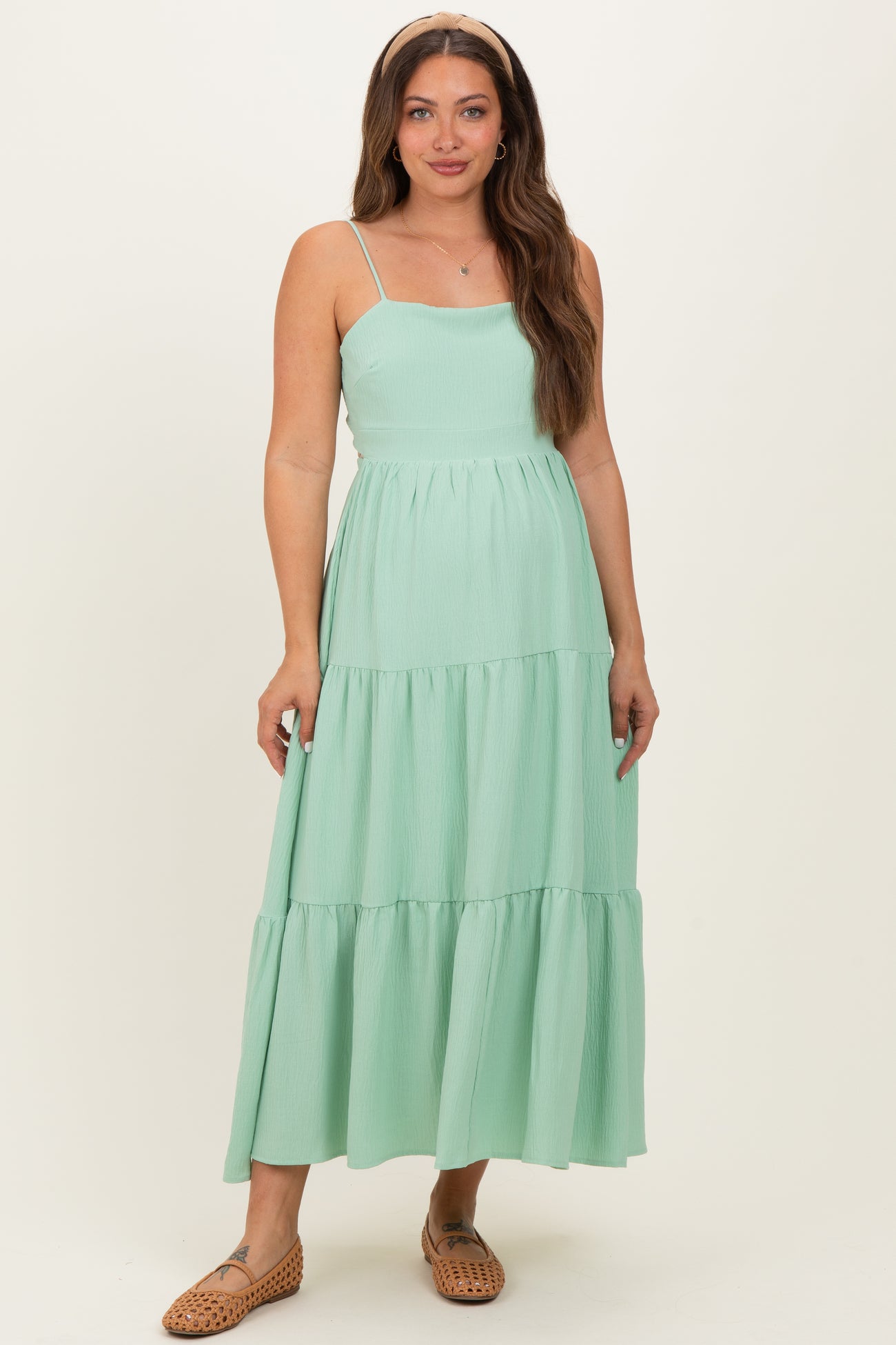 woman wearing a mint green tiered maternity dress with spaghetti straps and a fitted bodice