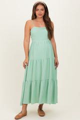 woman wearing a mint green tiered maternity dress with spaghetti straps and a fitted bodice