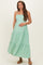 woman wearing a mint green maternity maxi dress with tiered ruffles and holding her baby bump