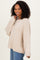 woman wearing a beige oversized knit sweater with long sleeves and relaxed fit paired with blue jeans
