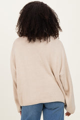 woman wearing a beige oversized knit sweater, seen from the back, paired with light blue jeans