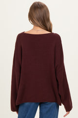 woman wearing a burgundy oversized knitted maternity sweater with a wide neckline and long sleeves, seen from the back