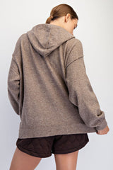 woman wearing a brown oversized hoodie from the back, paired with dark quilted shorts