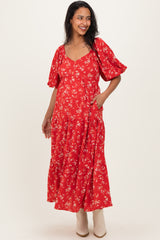 woman wearing a red floral maternity maxi dress with short puff sleeves and pockets, showcasing her baby bump