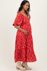 woman wearing a red floral maternity maxi dress and holding her baby bump