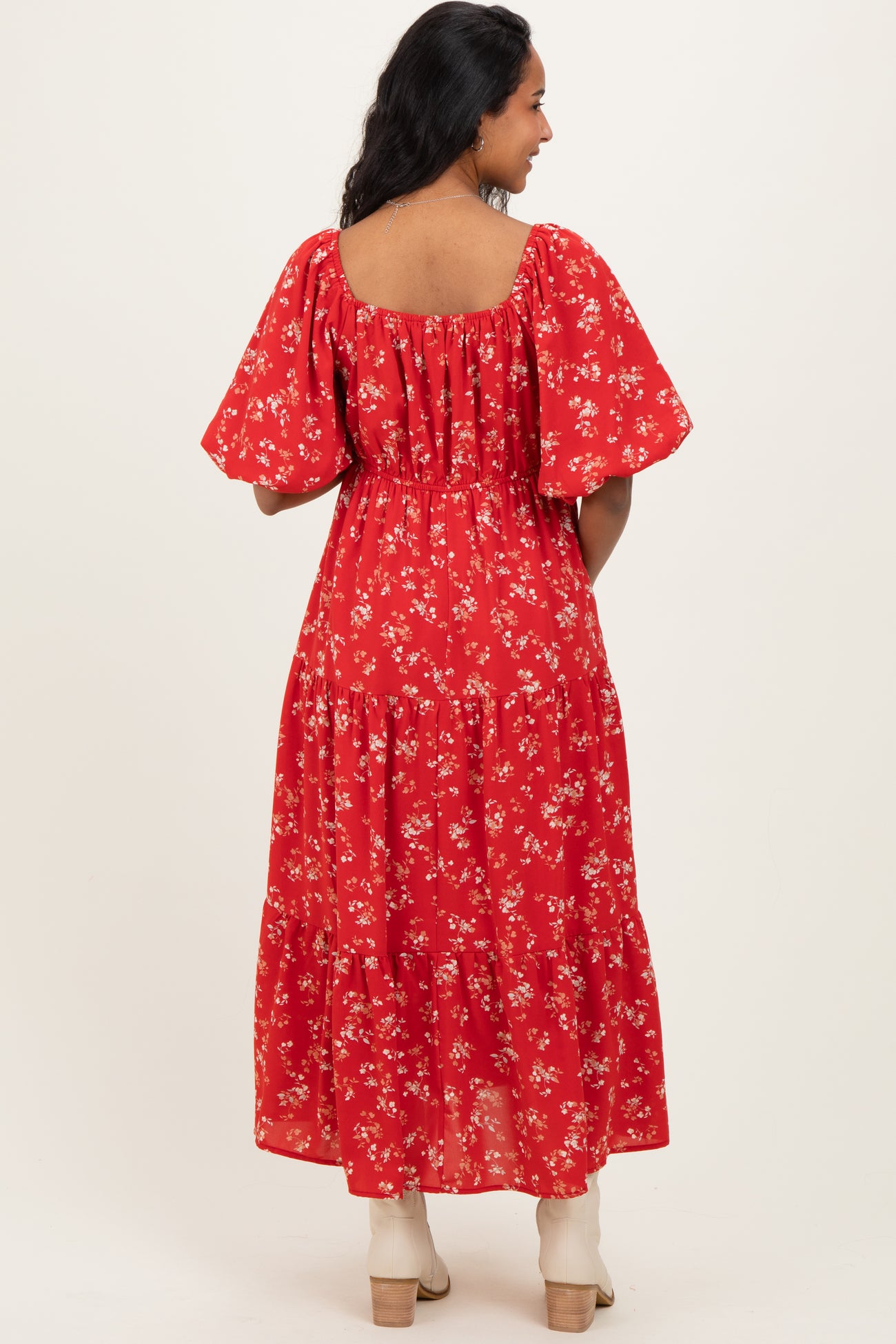 woman wearing a red floral maternity maxi dress with puff sleeves and a flowing skirt, showing a baby bump from behind