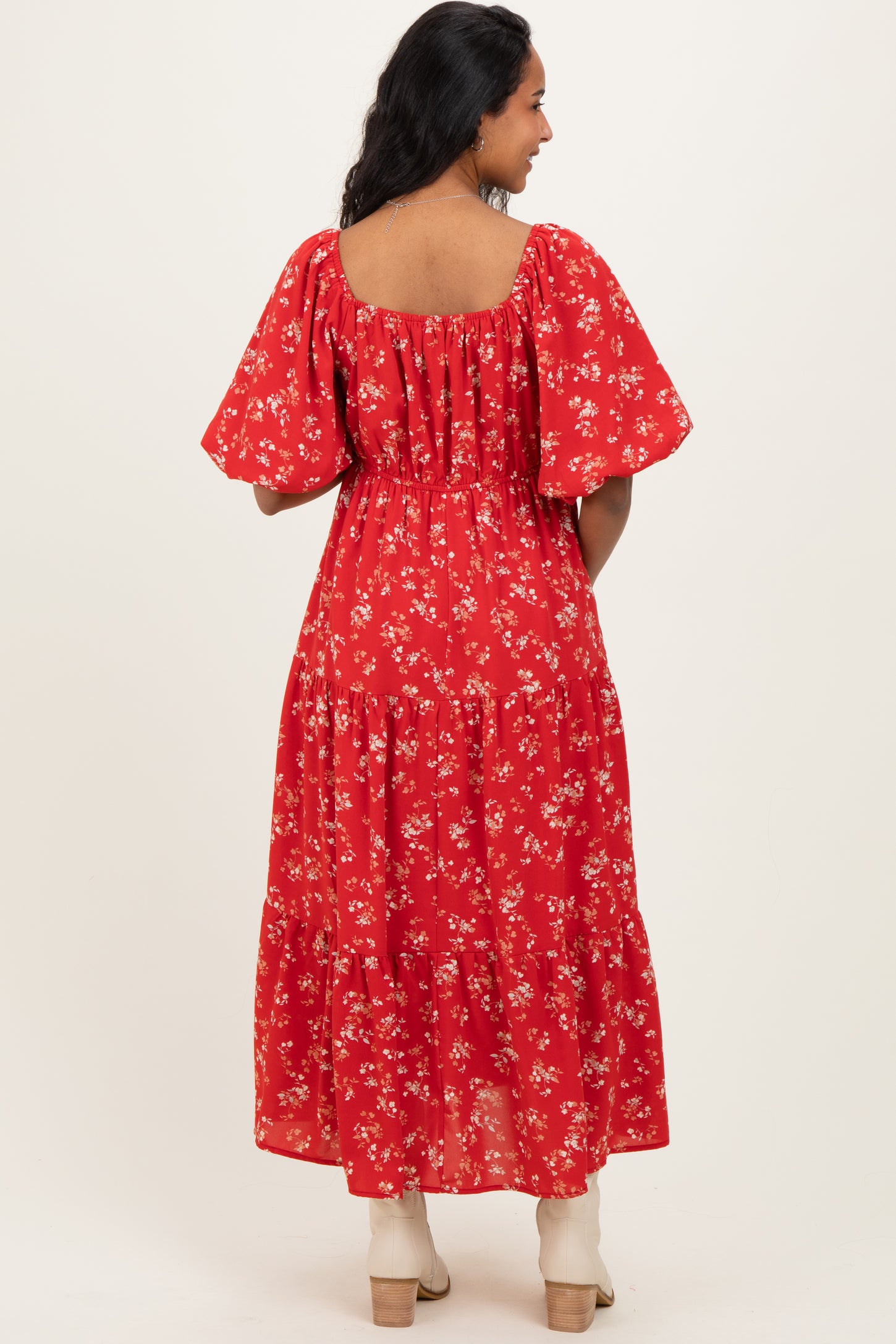 woman wearing a red floral maternity maxi dress with puff sleeves and a flowing skirt, showing a baby bump from behind