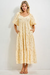 woman wearing a yellow floral tiered maxi dress with puff sleeves and pockets