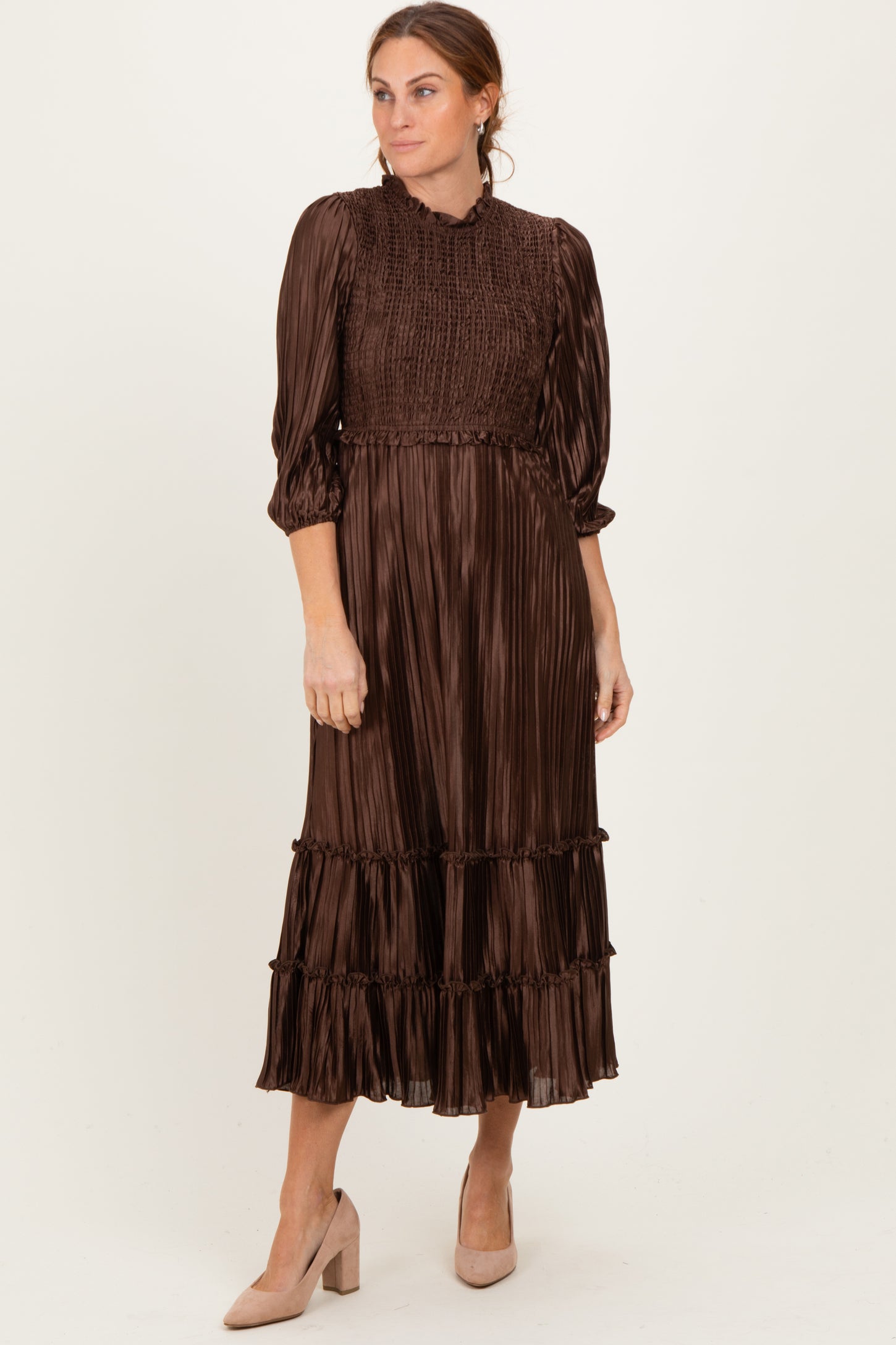 woman wearing a brown pleated midi dress with smocked bodice and tiers, paired with beige heels