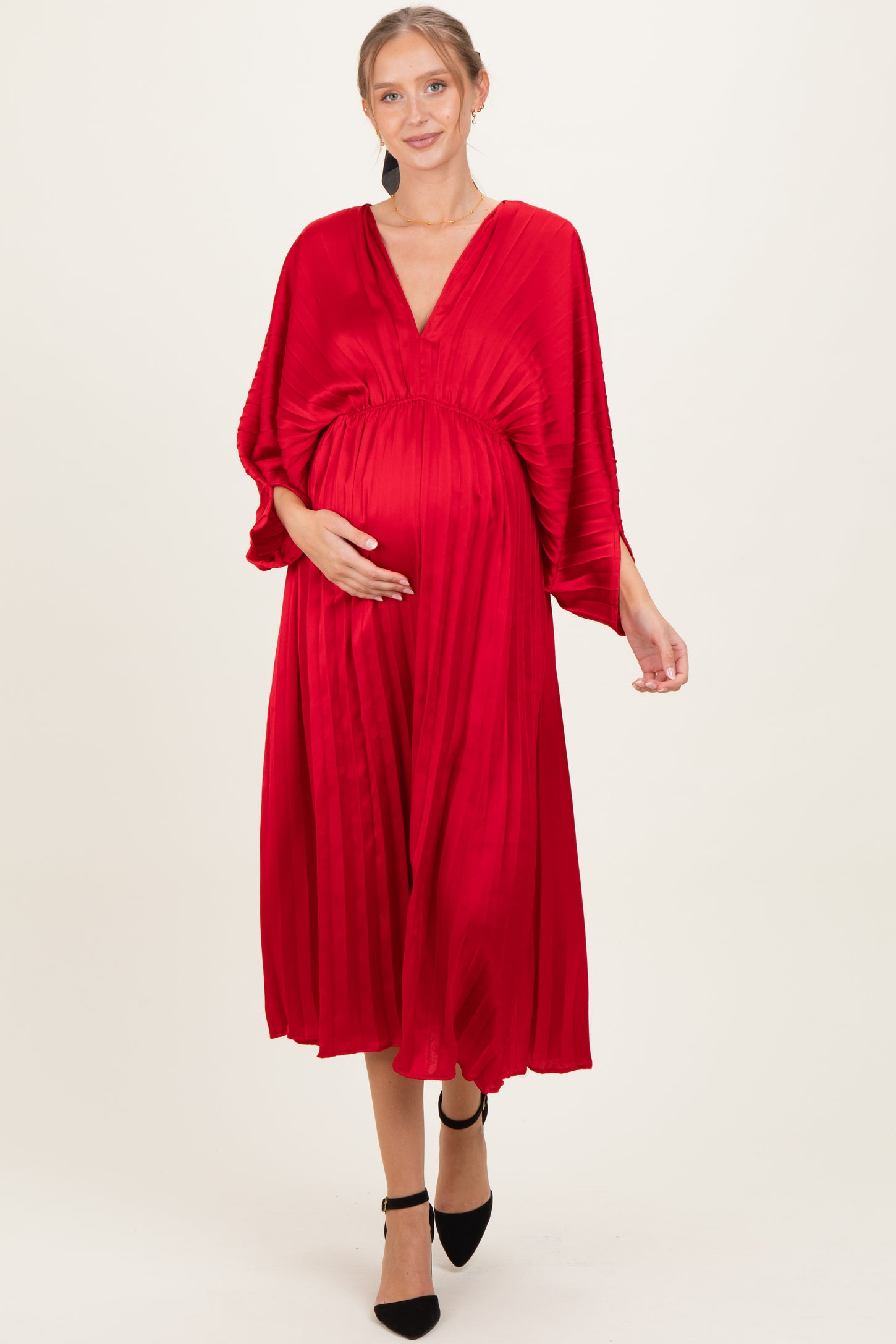 woman wearing a vibrant red maternity dress with pleated details and a v-neckline, showcasing her baby bump
