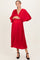 woman wearing a red pleated maternity dress with a deep v-neck and holding her baby bump
