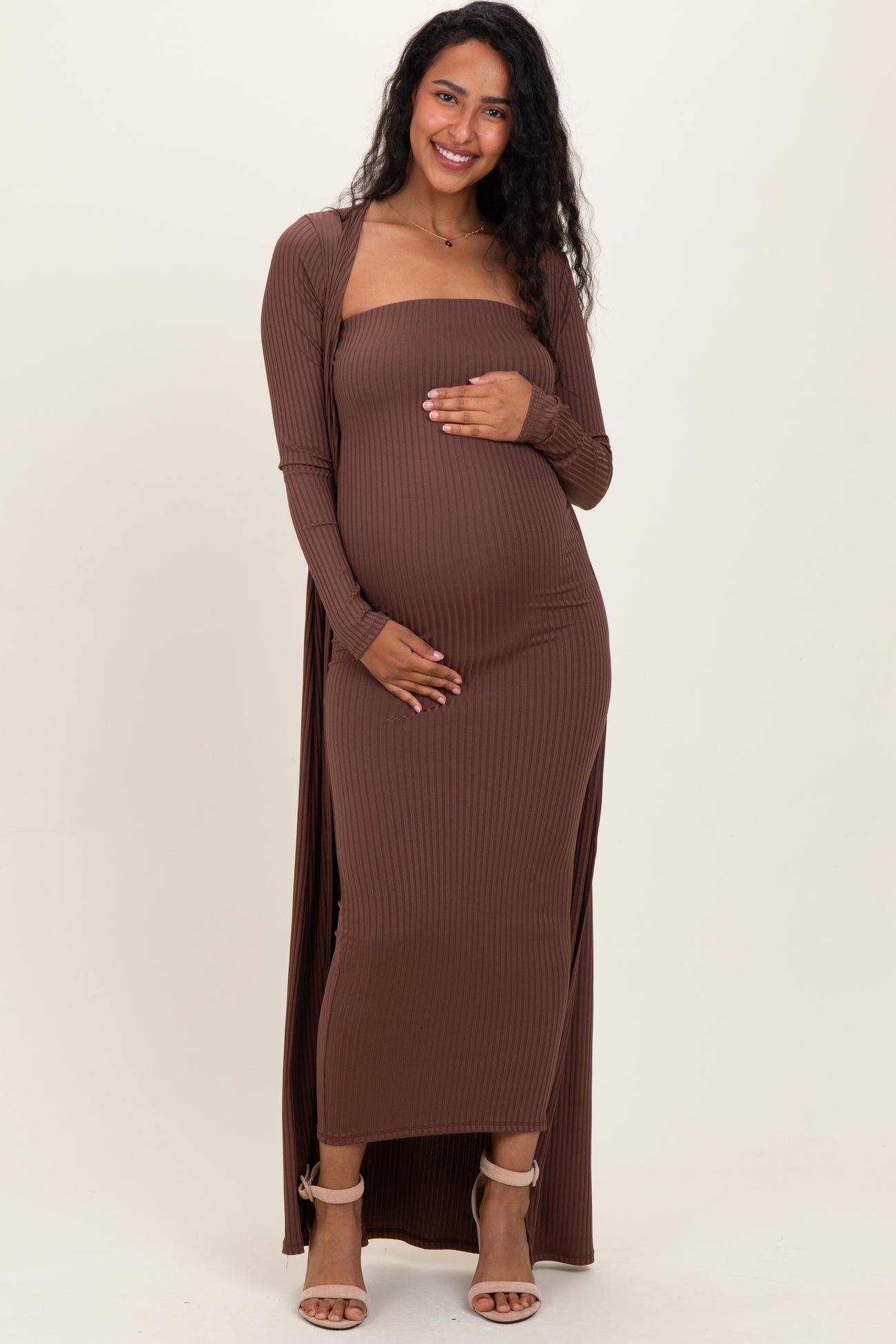 woman wearing a brown ribbed maternity maxi dress with long sleeves and a visible baby bump