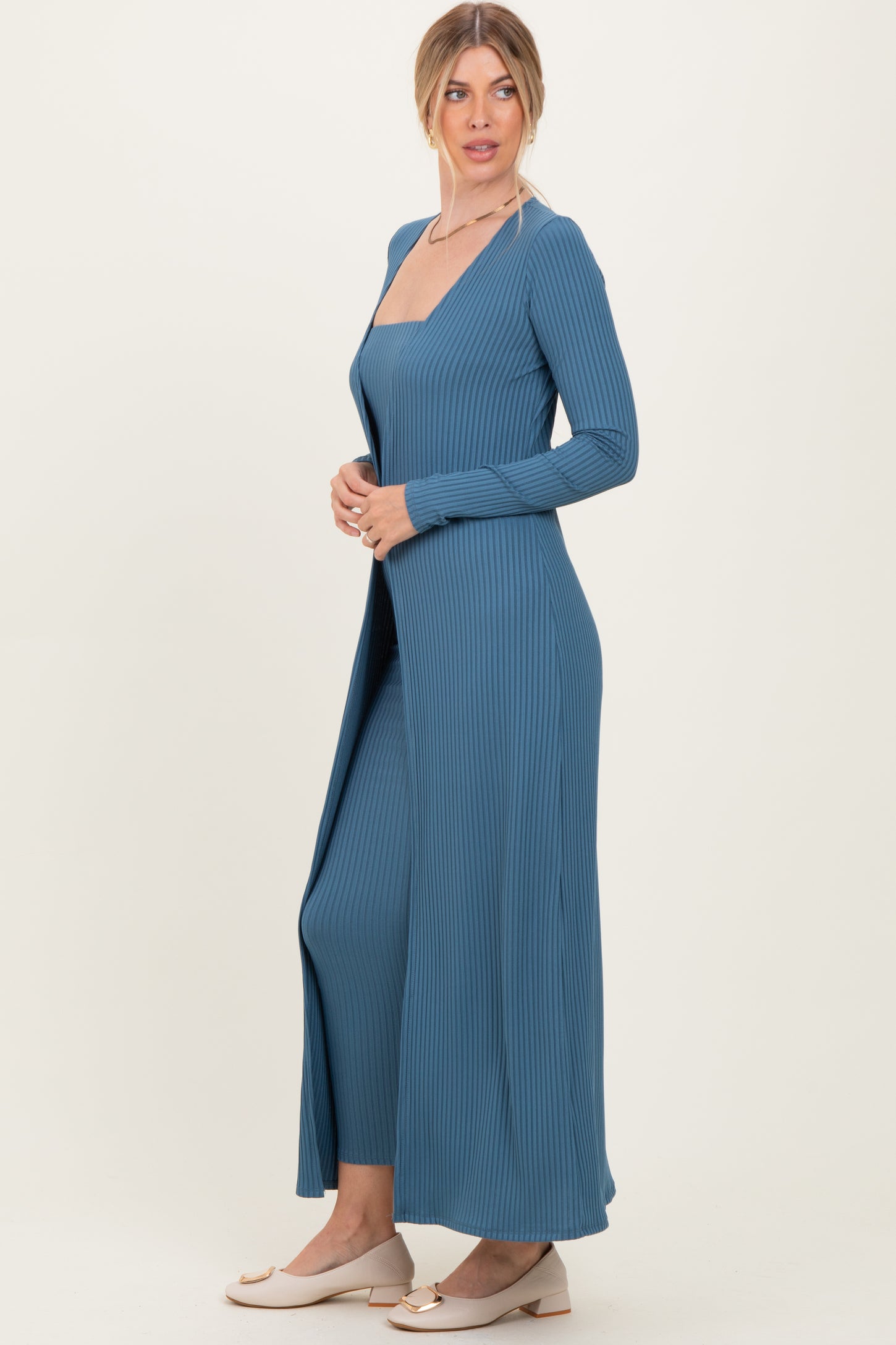 woman wearing a blue ribbed long sleeve dress with a deep neckline and side slits
