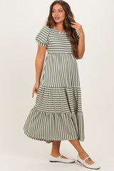 woman wearing a striped green and white maternity dress with short sleeves and a tiered skirt, holding her hair back